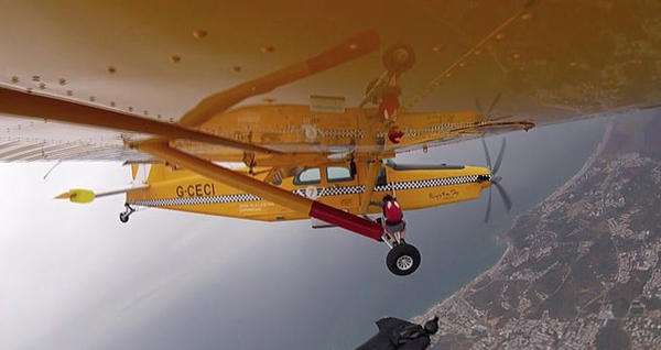 葡萄牙跳伞员爬出飞机外接翼装飞行者手中香蕉