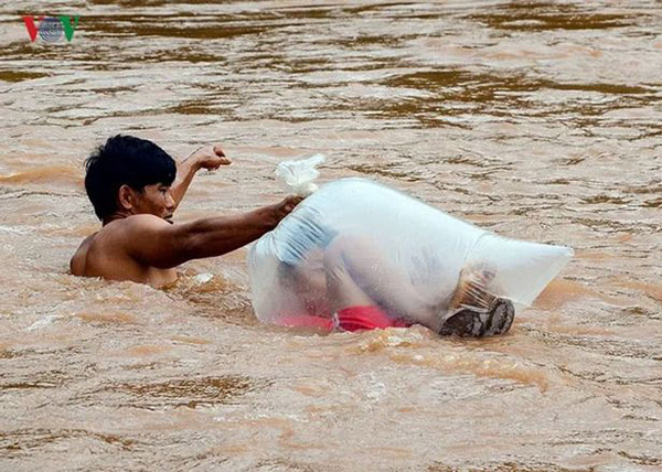 越南河流洪水泛滥 家长用塑料袋运孩子过河上学