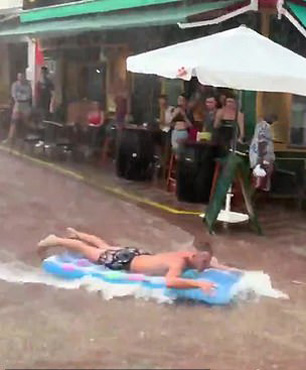 西班牙度假者遇暴雨天气“苦中作乐” 街道上玩冲浪
